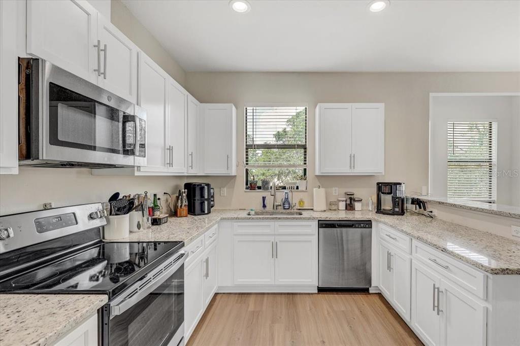 7314 Madrid Road Weeki Wachee, FL 34613 - Photo 15 of 54 a kitchen with stainless steel appliances granite countertop white cabinets sink stove and microwave