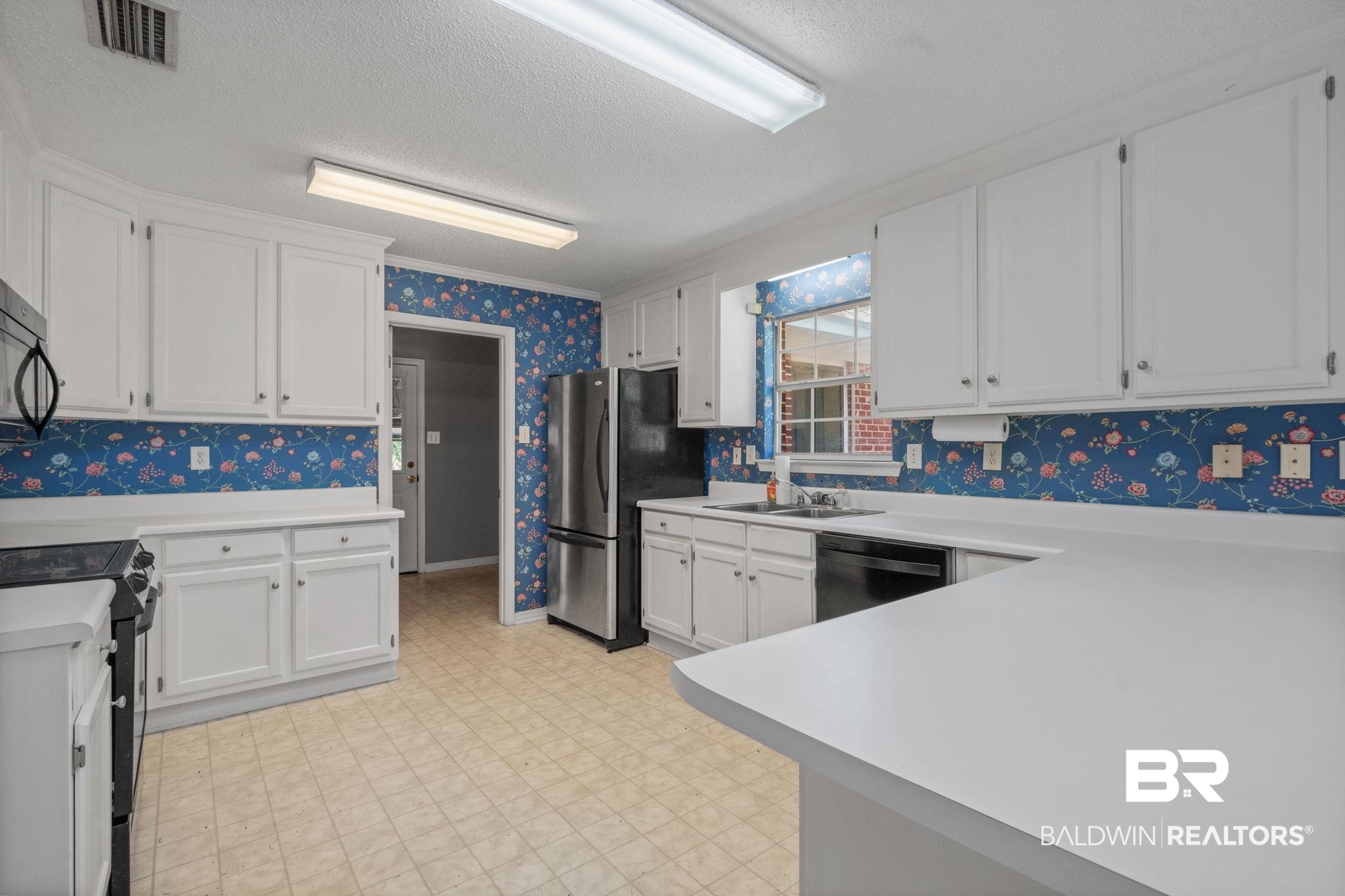 1340 Wellsley Court Mobile, AL 36695 - Photo 16 of 37 Kitchen featuring wallpapered walls, white cabinets, a textured ceiling, light countertops, and black appliances