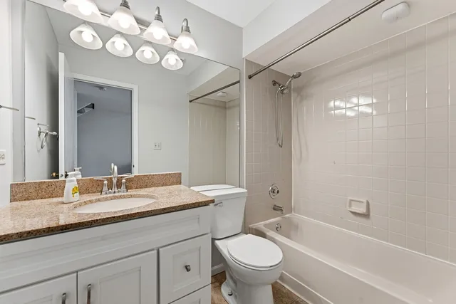 a bathroom with a granite countertop sink a toilet a mirror a bathtub and shower