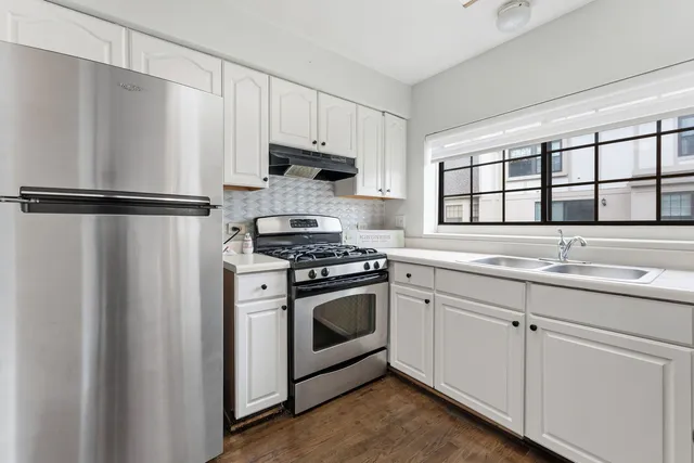 a kitchen with stainless steel appliances a sink cabinets and a window