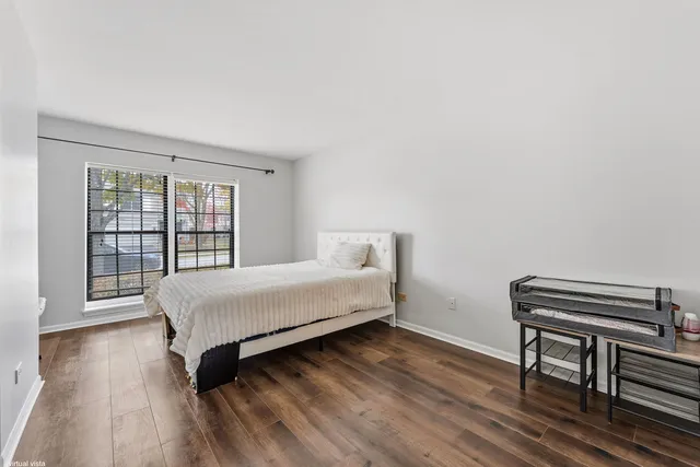 a bedroom with a bed table and two windows