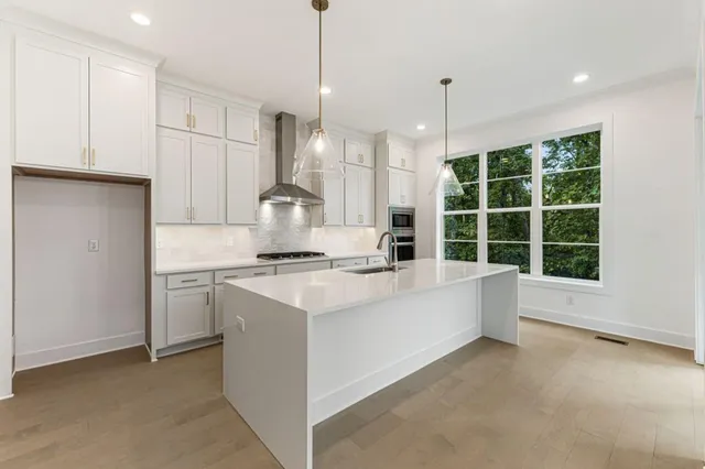 a kitchen with stainless steel appliances a sink a stove and a wooden floors