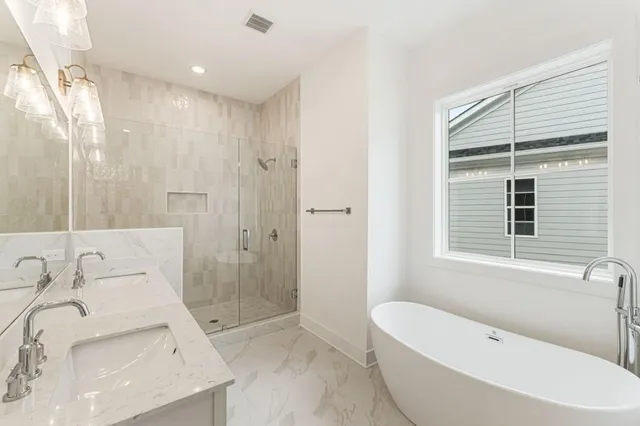a bathroom with a bathtub shower sink vanity mirror and toilet