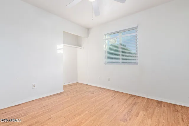 a view of empty room with wooden floor and fan