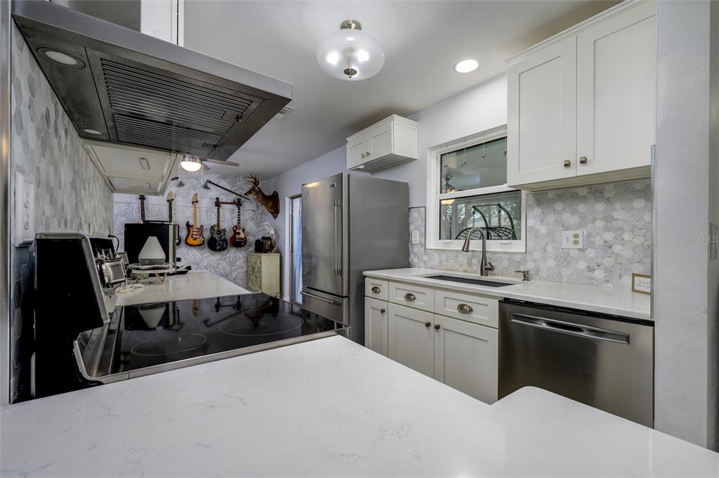 1472 Queen Anne Drive Palm Harbor, FL 34684 - Photo 9 of 34 a kitchen with stainless steel appliances kitchen island granite countertop a sink dishwasher stove and refrigerator