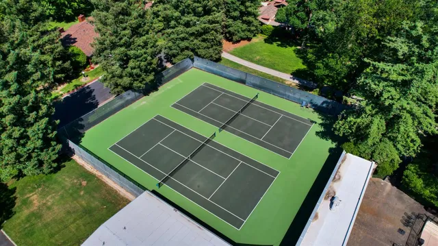a view of a tennis ground with large trees