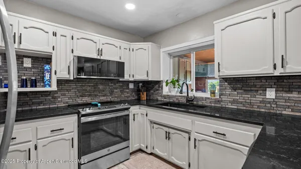 a kitchen with stainless steel appliances white cabinets a sink and a stove