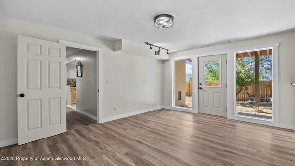 an empty room with wooden floor and windows