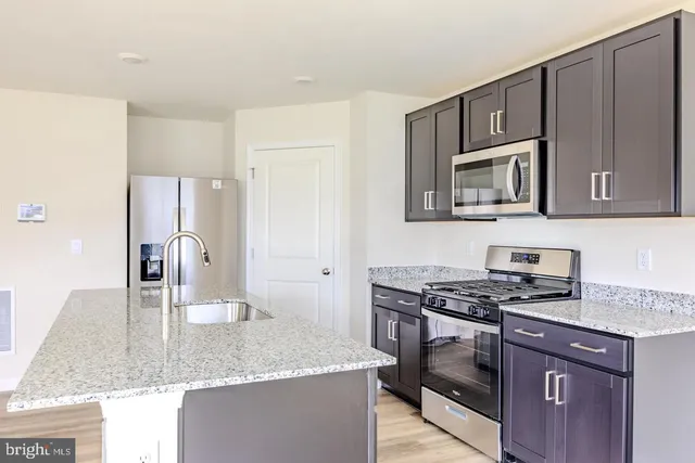 a kitchen with granite countertop a sink stove and refrigerator