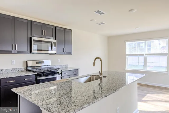 a kitchen with stainless steel appliances granite countertop a sink stove and microwave