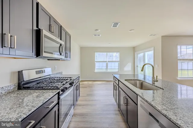 a kitchen with granite countertop a stove a sink and a microwave