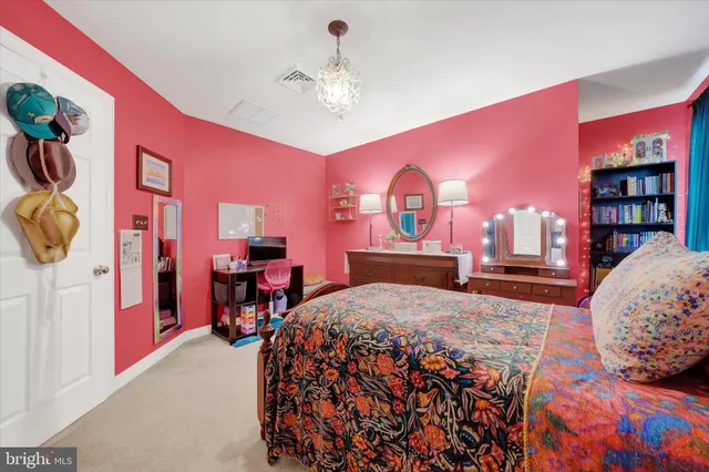 a bedroom with a bed and dresser with wooden floor
