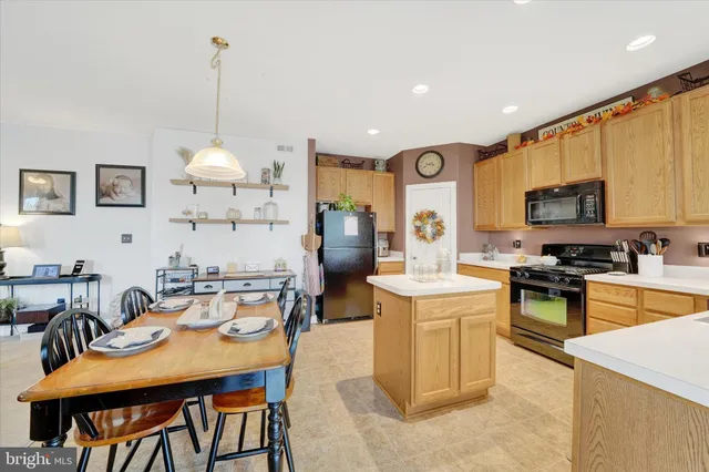 a kitchen with stainless steel appliances kitchen island granite countertop a table chairs and a refrigerator