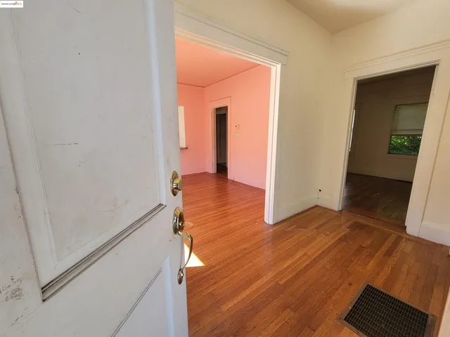 an empty room with wooden floor fireplace and windows