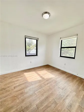 a view of an empty room with window and wooden floor