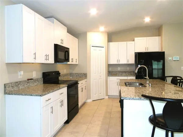 a kitchen with a stove a sink a microwave a refrigerator and cabinets