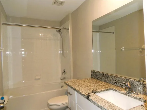 a bathroom with a granite countertop sink a toilet and shower