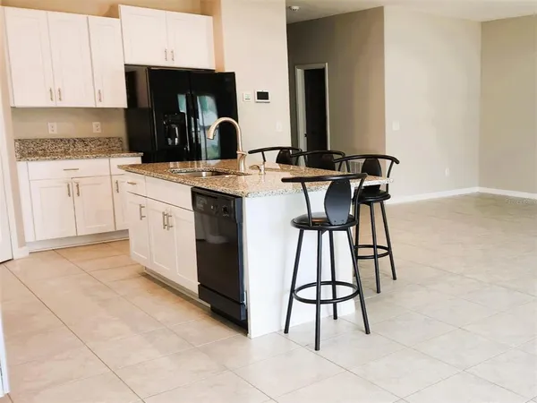a kitchen with a sink a stove and white cabinets