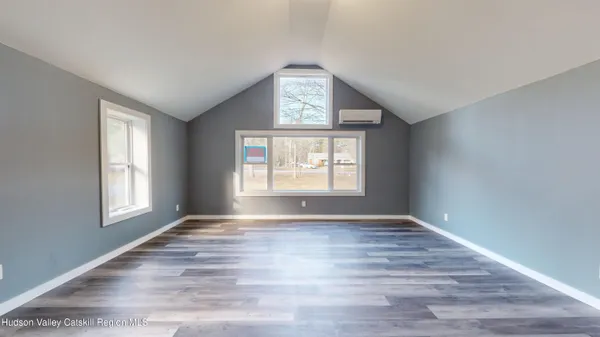 a view of an empty room with wooden floor and window