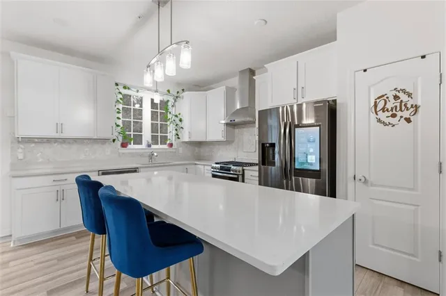 a kitchen with stainless steel appliances granite countertop a sink a stove a refrigerator and island with wooden floor