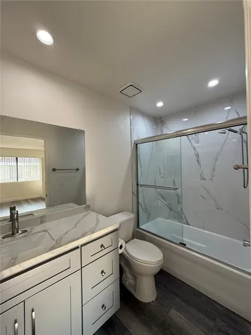 a bathroom with a granite countertop sink toilet a mirror and shower