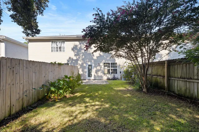 a view of a backyard with large trees and wooden fence