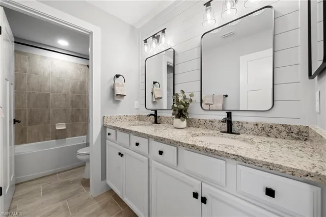 a bathroom with a granite countertop sink double mirror shower and a bathtub