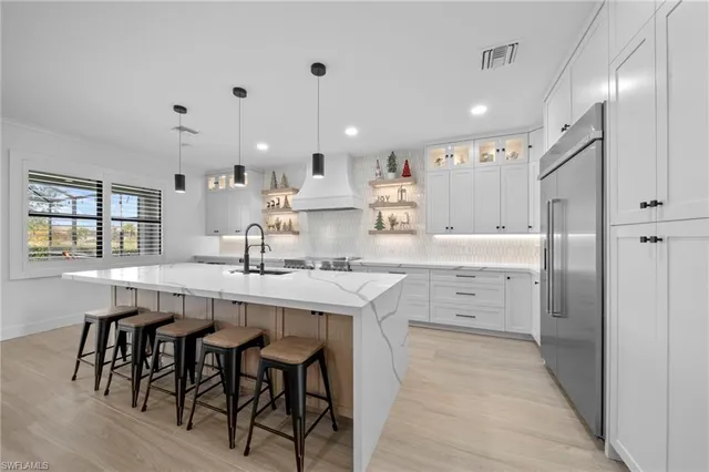 a kitchen with stainless steel appliances kitchen island granite countertop a table chairs sink and cabinets
