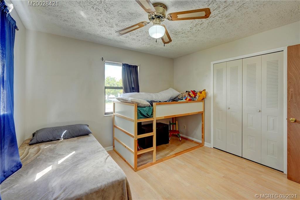 4918 Southeast Salvatori Road Stuart, FL 34997 - Photo 14 of 37 a bedroom with a bed and a chandelier