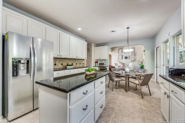 a kitchen with granite countertop stainless steel appliances a refrigerator a stove a table and chairs