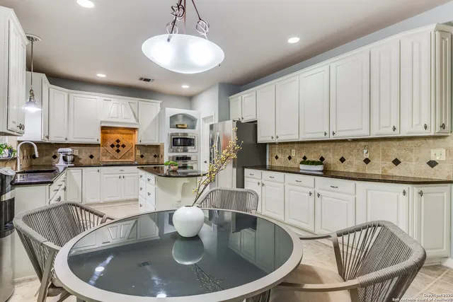 a kitchen with stainless steel appliances granite countertop a sink a stove a microwave a refrigerator and white cabinets