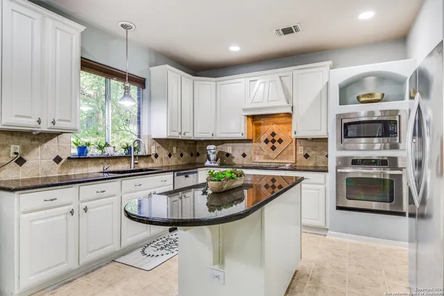 a kitchen with stainless steel appliances granite countertop a sink window and cabinets