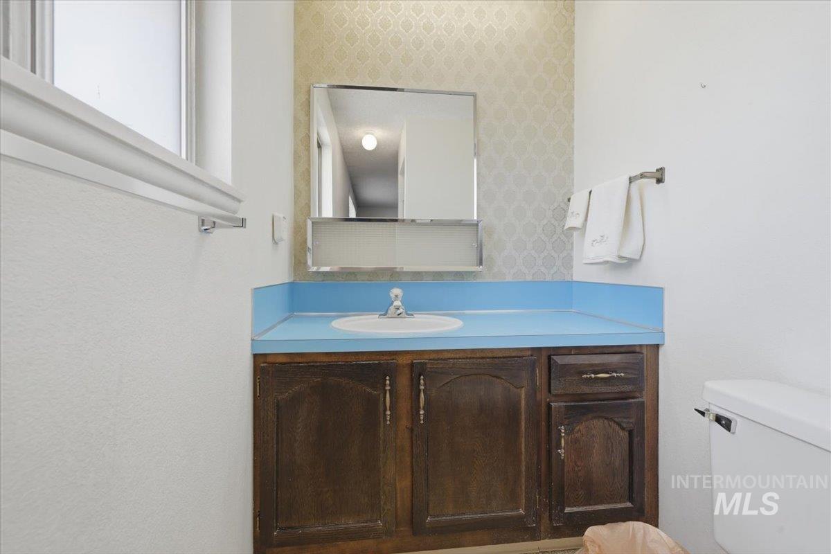 1311 North Middleton Road Nampa, ID 83651 - Photo 28 of 49 Bathroom vanity featuring a blue countertop, integrated white sink, and wood-finish cabinetry with brass-tone hardware