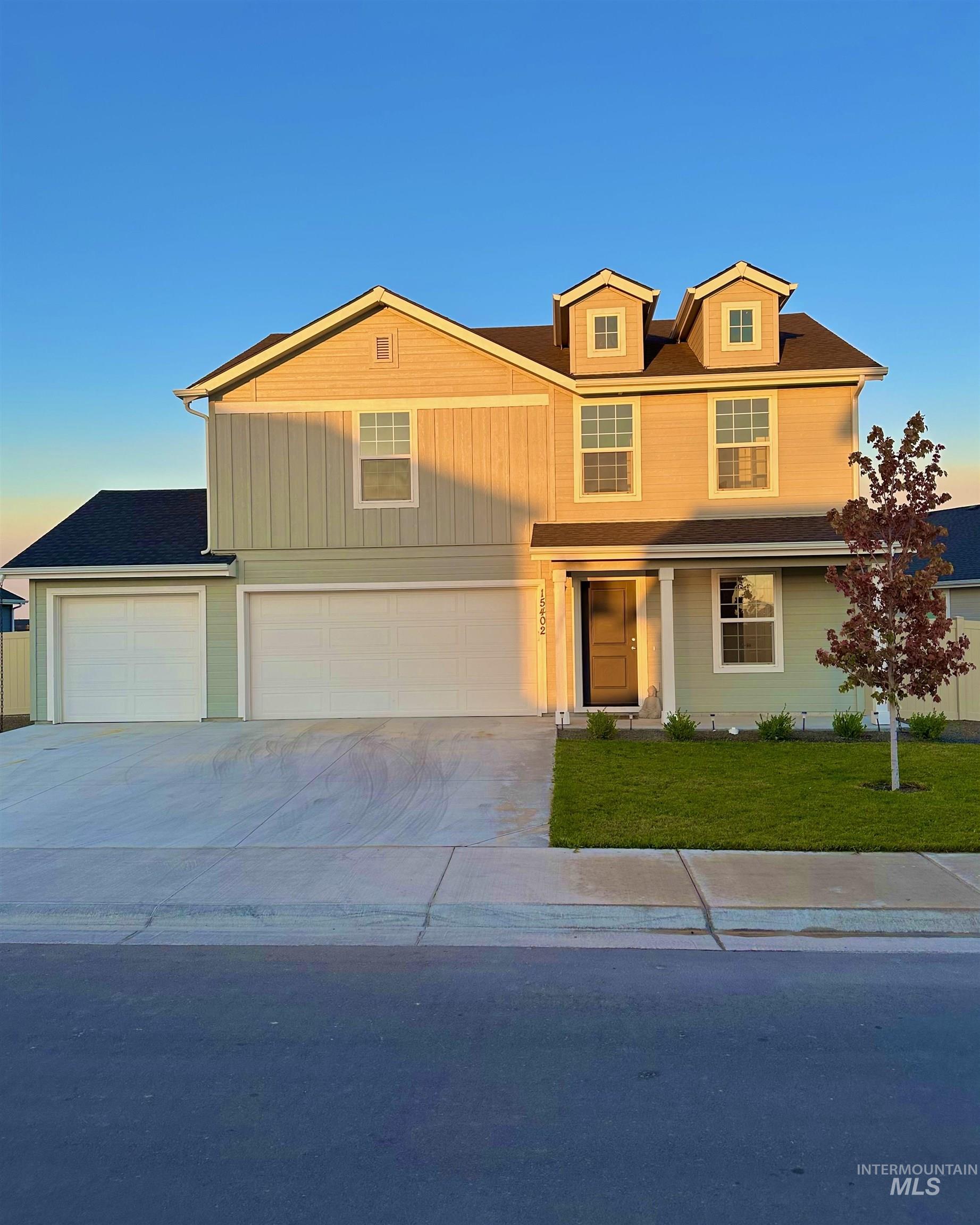 Traditional-style home with driveway, a yard, covered porch, and a garage