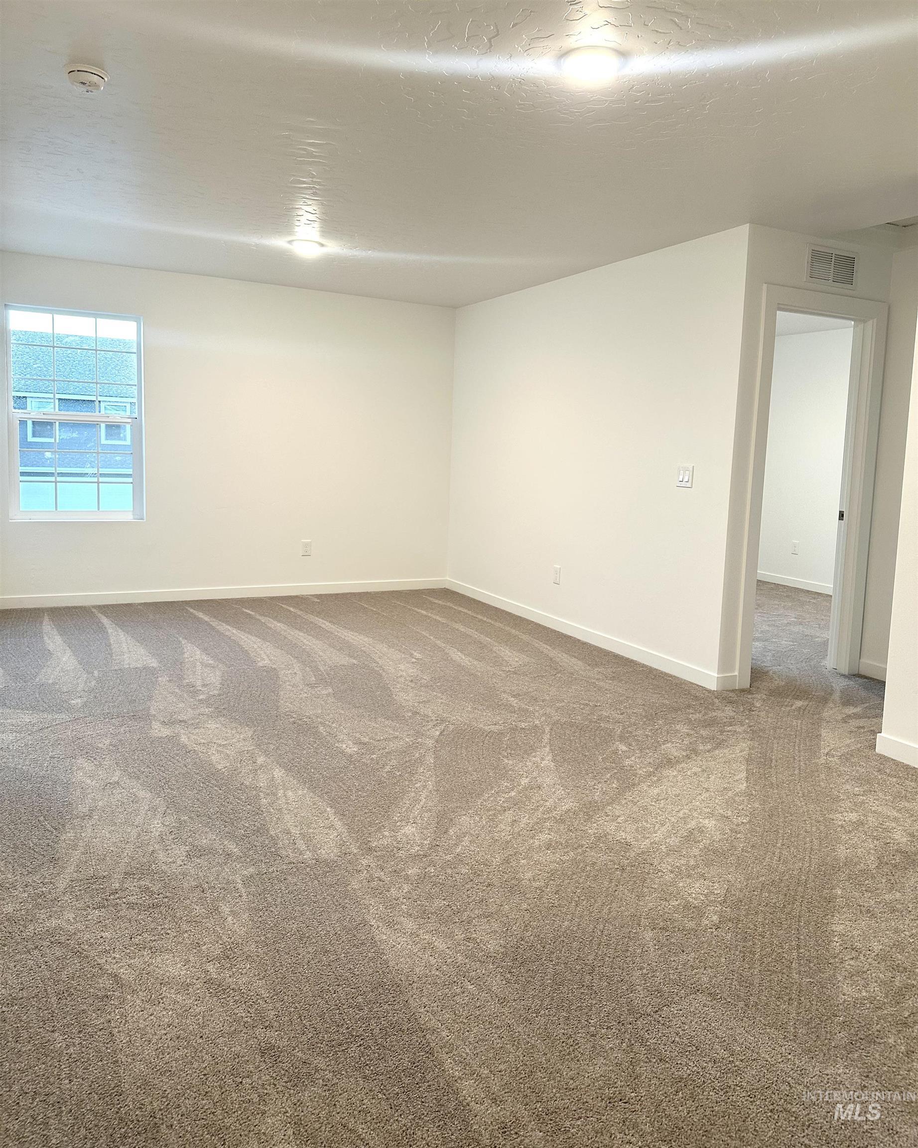 15402 Nimbus Way Caldwell, ID 83607 - Photo 5 of 9 Carpeted spare room featuring a textured ceiling and baseboards