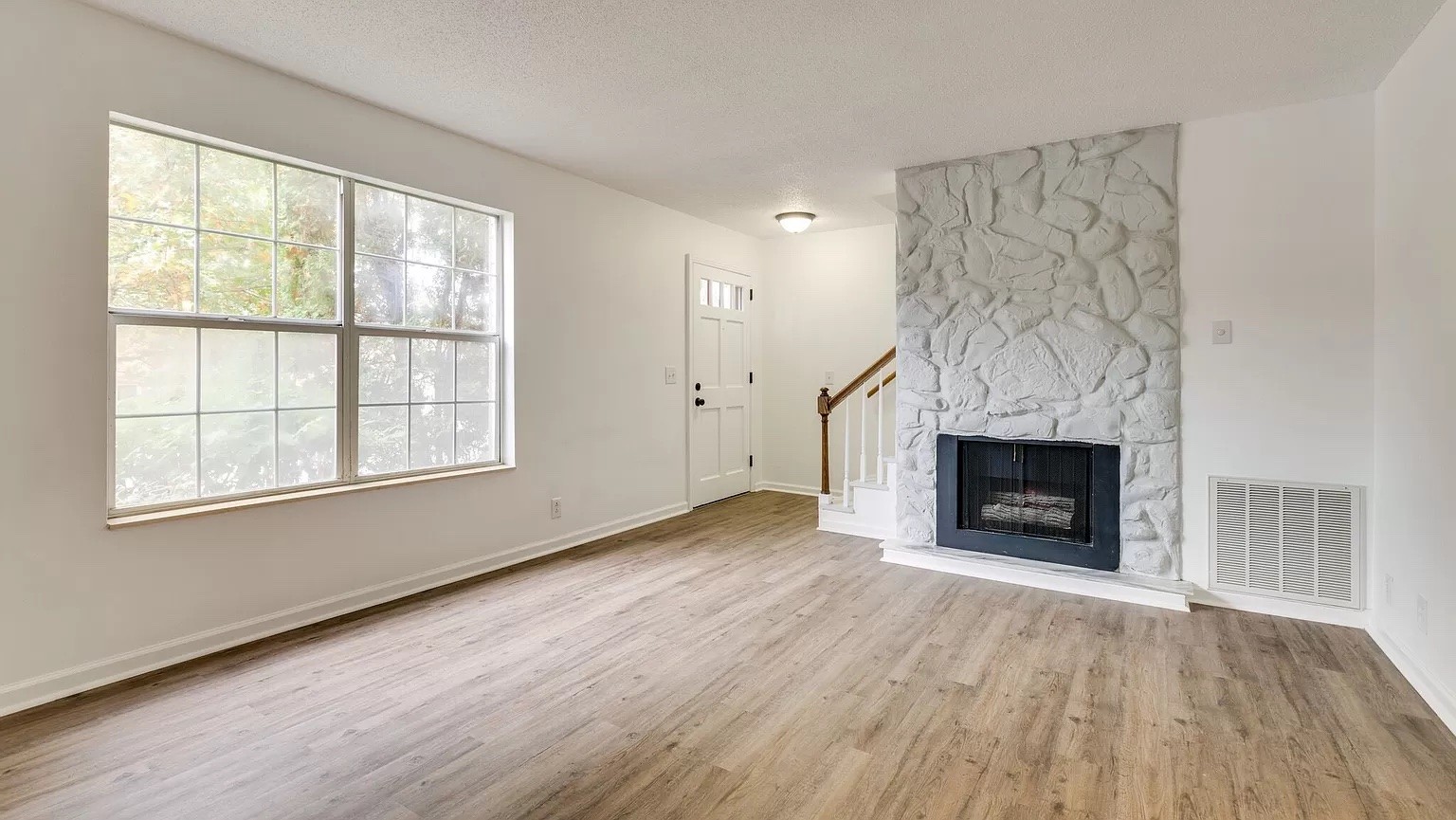 an empty room with windows a fireplace and wooden floor