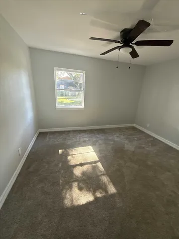 an empty room with a ceiling fan and window