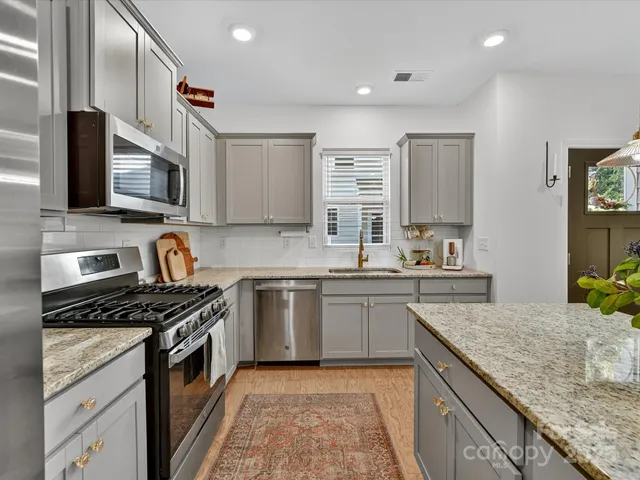 a kitchen with stainless steel appliances granite countertop a stove top oven a sink dishwasher and microwave oven