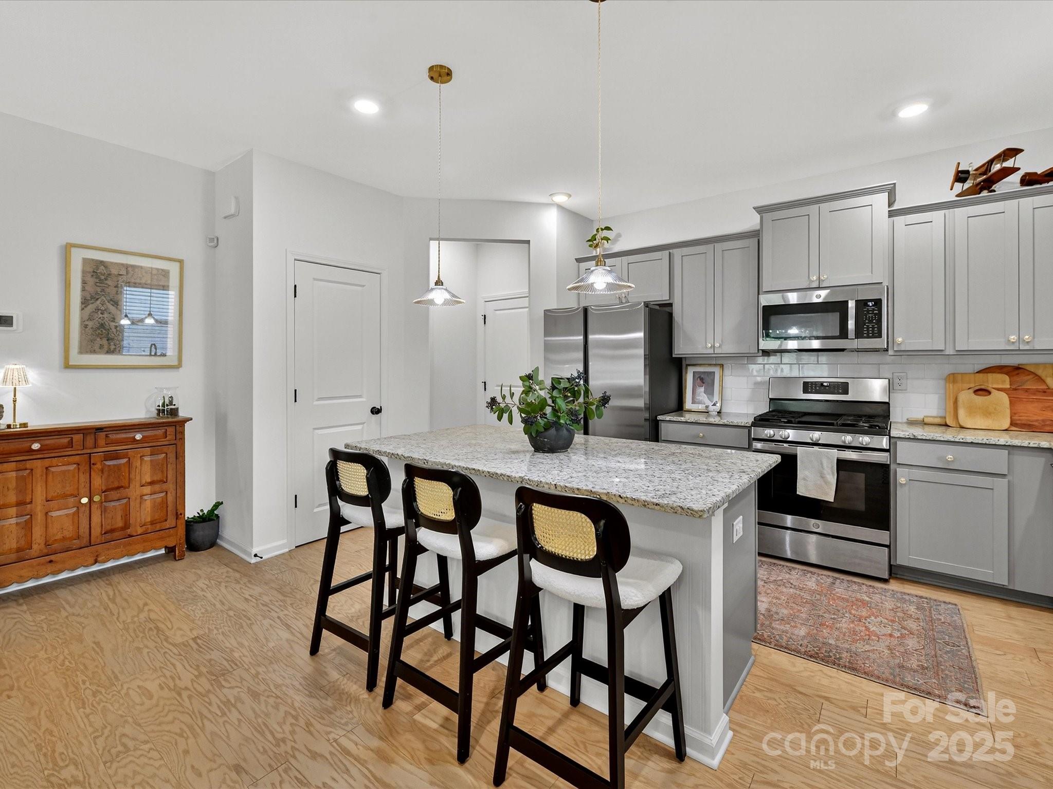 230 Quinn Road Matthews, NC 28104 - Photo 13 of 35 a kitchen with stainless steel appliances kitchen island granite countertop a table chairs sink and cabinets