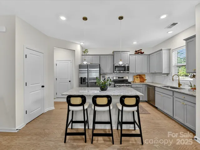 a kitchen with stainless steel appliances granite countertop a dining table chairs and white cabinets