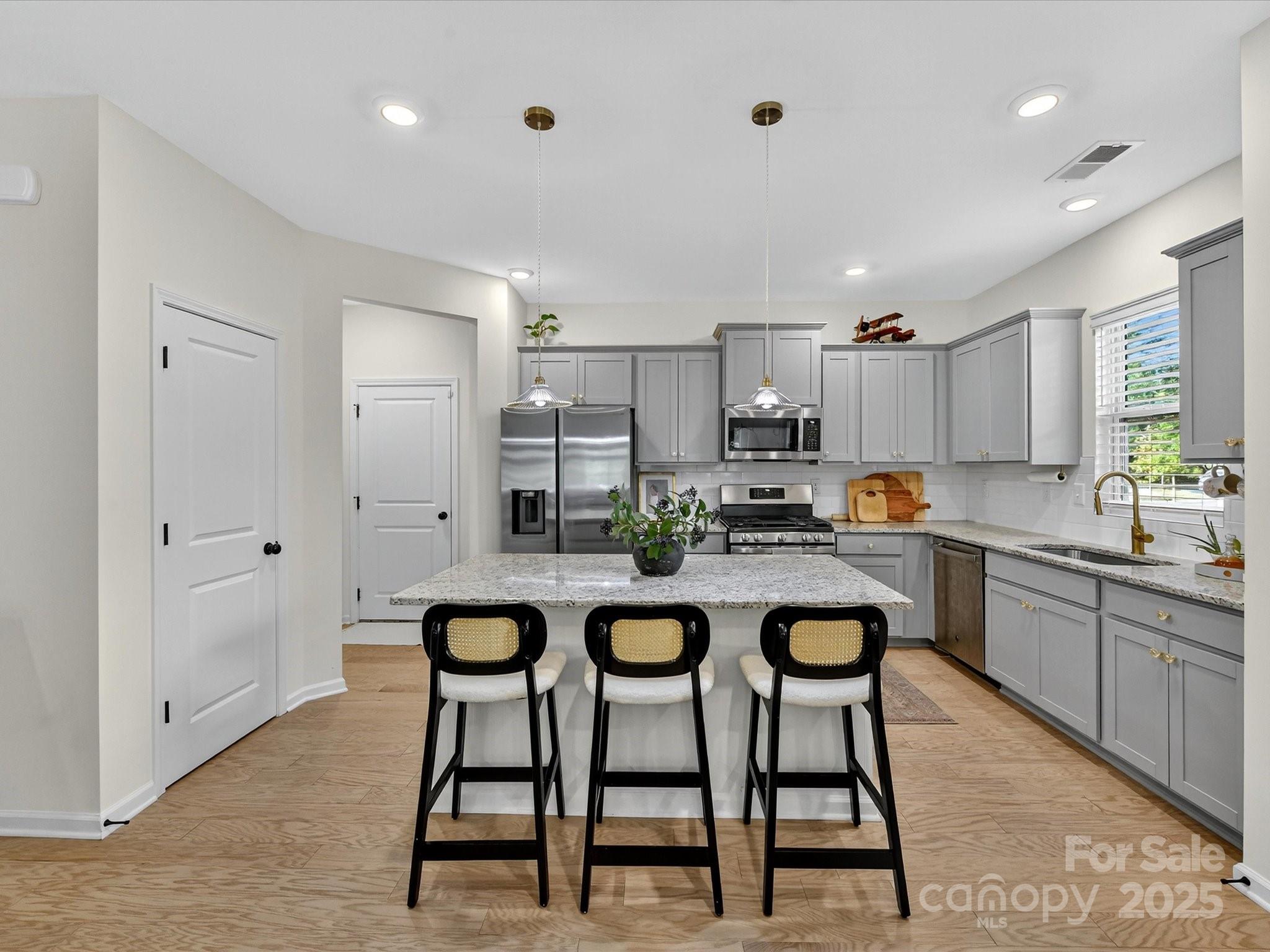 230 Quinn Road Matthews, NC 28104 - Photo 8 of 35 a kitchen with stainless steel appliances granite countertop a dining table chairs and white cabinets