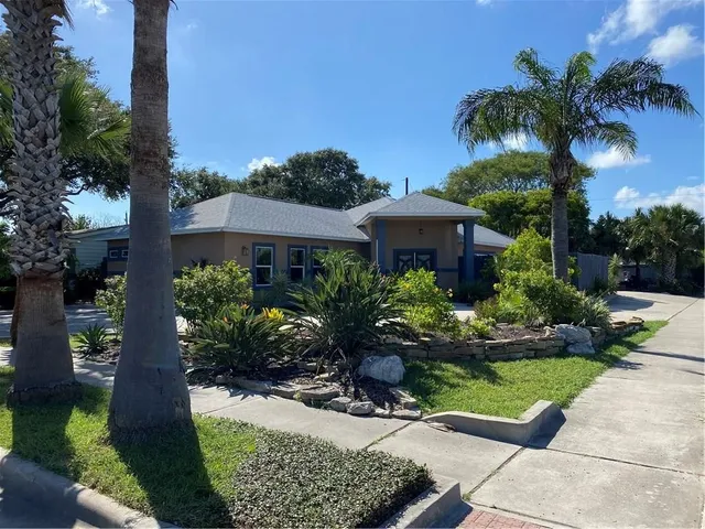 a front view of a house with a yard and potted plants