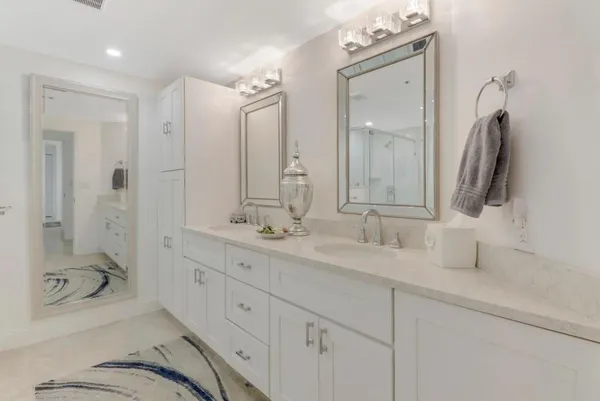 a bathroom with a double vanity sink mirror and bathtub