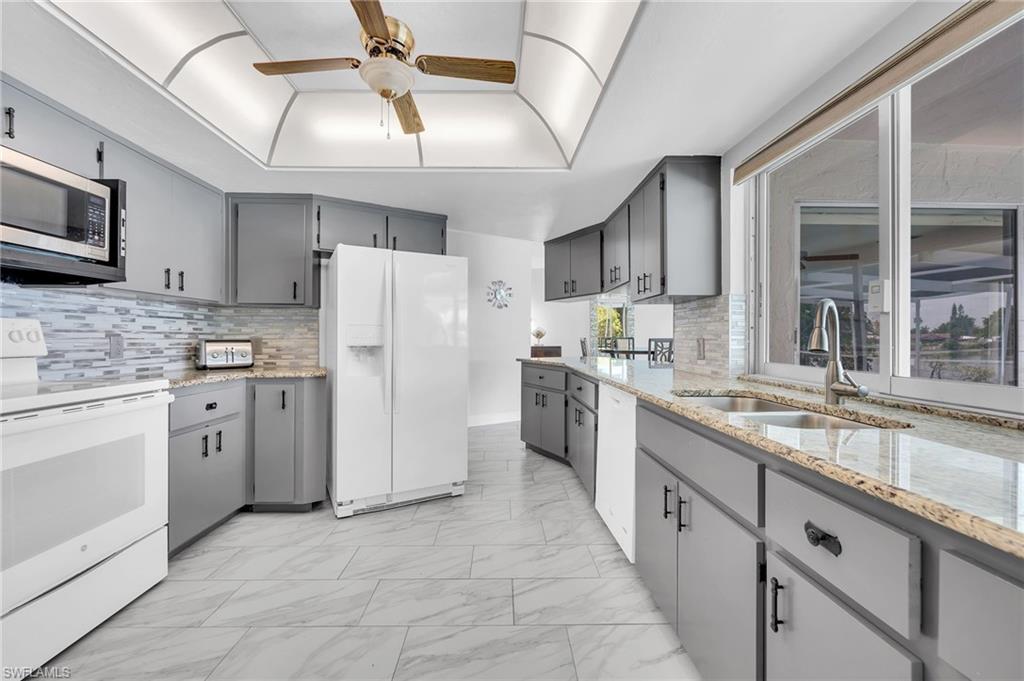 3065 50th Lane Southwest Naples, FL 34116 - Photo 8 of 31 a kitchen with white cabinets and white appliances