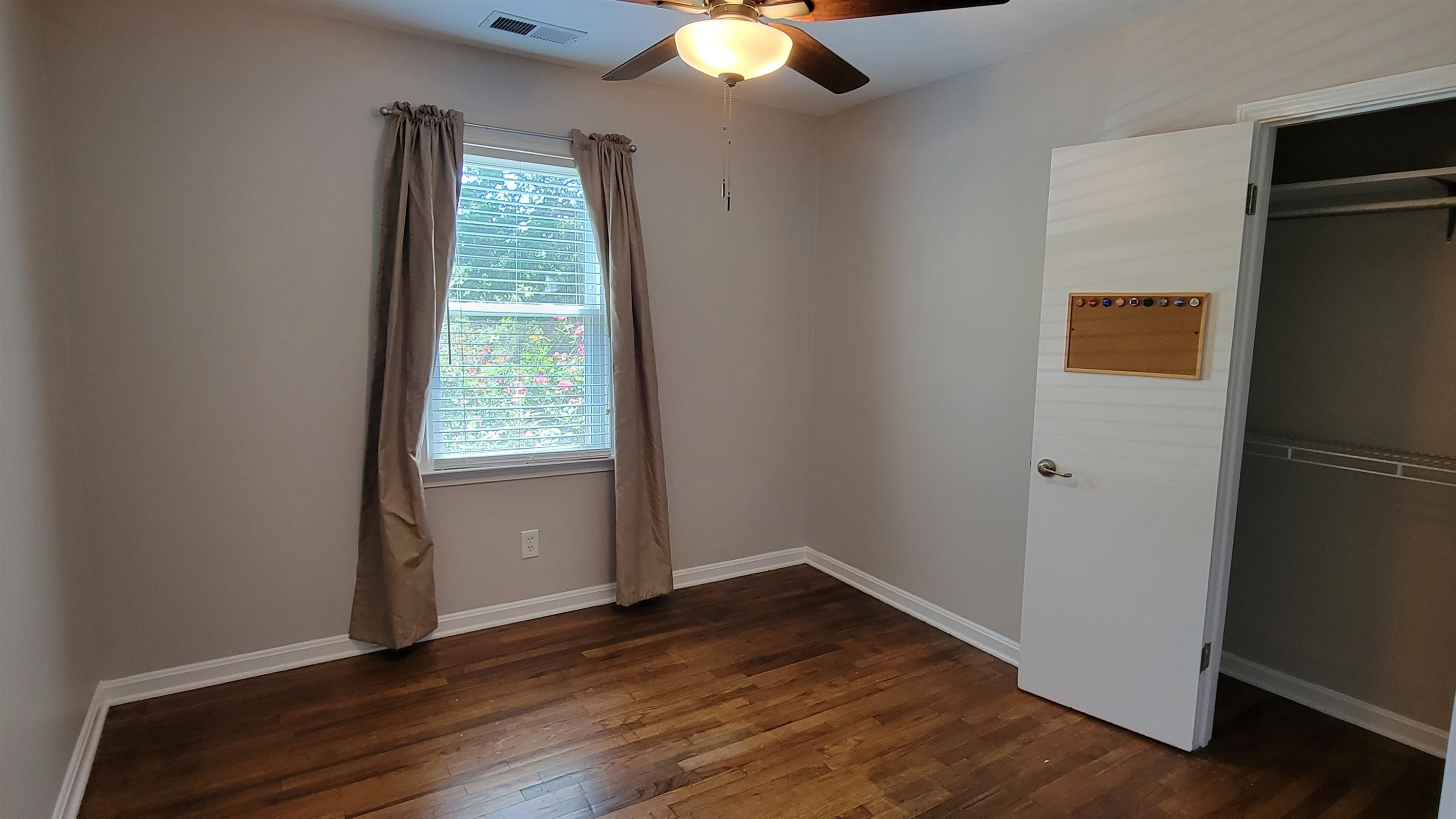 183 Spring Creek Law Road Jackson, TN 38305 - Photo 20 of 42 an empty room with wooden floor chandelier fan and windows