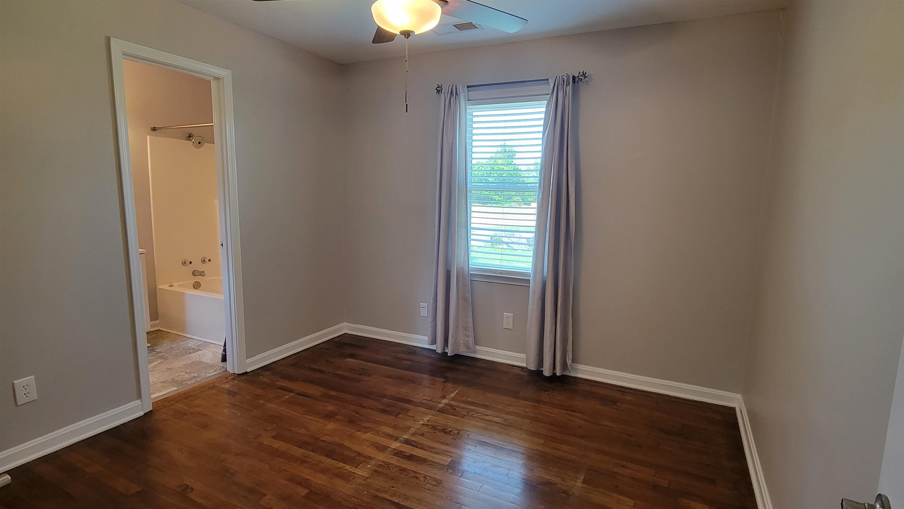 183 Spring Creek Law Road Jackson, TN 38305 - Photo 24 of 42 an empty room with wooden floor a ceiling fan and window