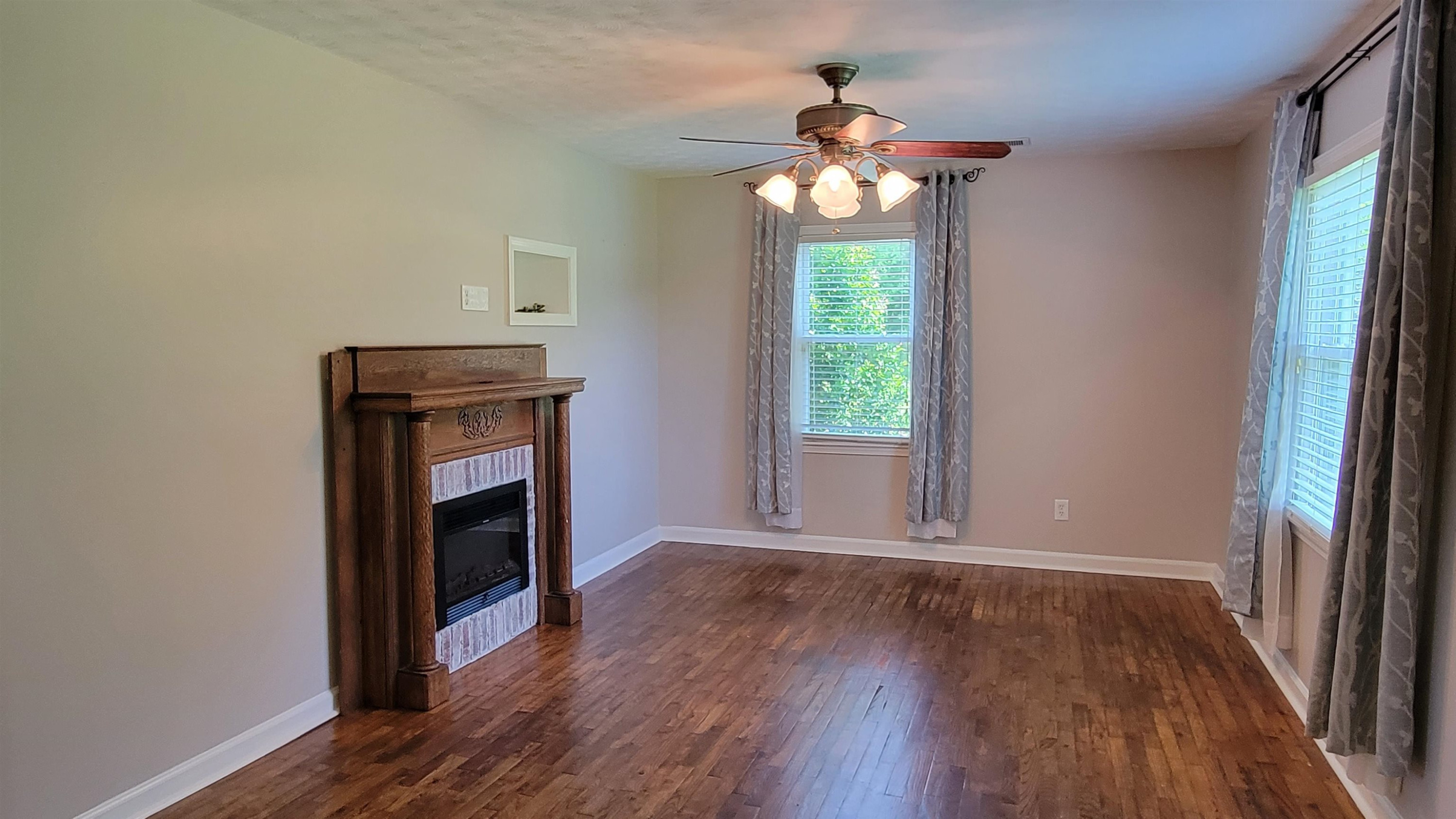 183 Spring Creek Law Road Jackson, TN 38305 - Photo 9 of 42 an empty room with wooden floor fireplace and window