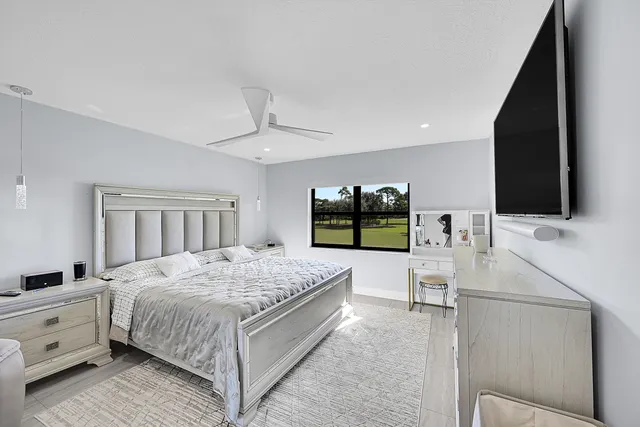 a bedroom with a large bed and a flat tv screen on dresser