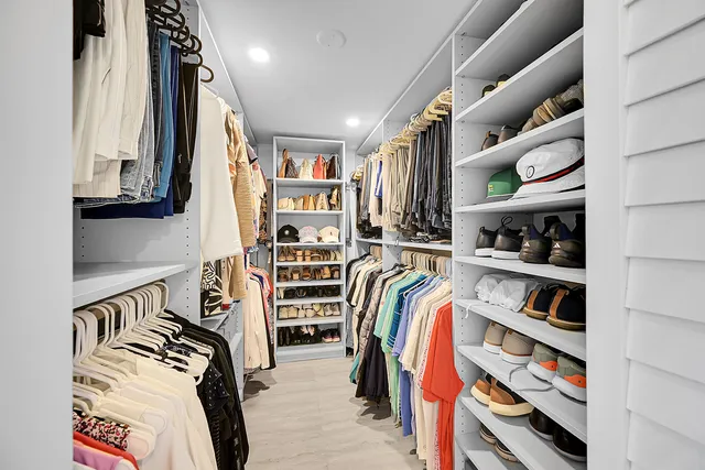 a view of walk in closet with clothes and shoes