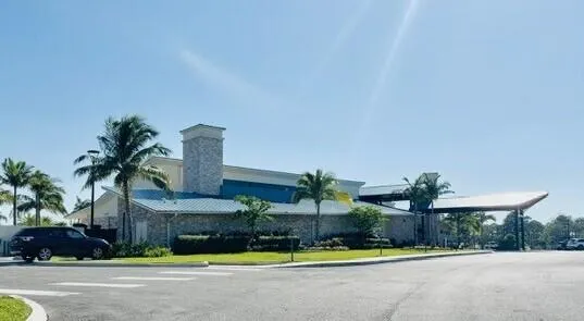 a front view of multi story residential apartment building with yard and green space